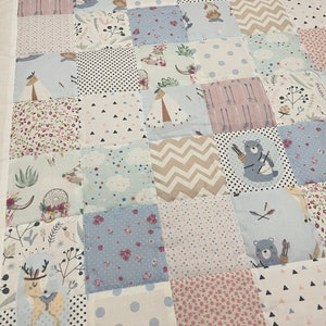 Könnte beinhalten: Eine Patchwork-Decke mit verschiedenen Mustern und Farben, darunter Rosa, Blau und Weiß. Die Decke zeigt verschiedene Tiermotive, darunter Bären, Hirsche und Eulen. Die Decke ist aus weichem, bequemem Stoff gefertigt und perfekt für ein Kinderzimmer oder ein Babyzimmer.