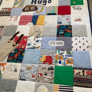 Op de afbeelding: Een patchwork quilt gemaakt van stofvierkanten met diverse patronen en kleuren. De quilt is gepersonaliseerd met de naam "Hugo" en de tekst "Born in 2022". Appliqué details zijn een ster en een dinosaurus.