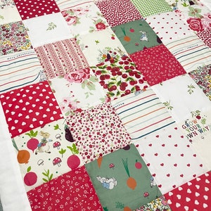Könnte beinhalten: Eine Patchwork-Decke mit weißem Hintergrund und verschiedenen bunten Quadraten mit Blumenmustern, roten Punkten und einem grünen Quadrat mit einer Hasenillustration. Der Text "Grow your own way" ist auf einem der Quadrate sichtbar.
