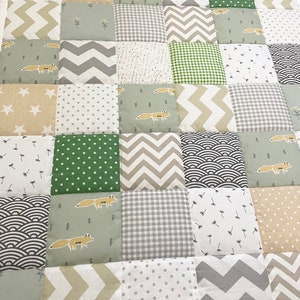 May include: A patchwork quilt with a variety of patterns in shades of green, gray, and beige. The quilt features a repeating pattern of foxes and other woodland creatures.