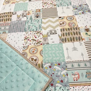 Può includere: Una trapunta per neonati di colore azzurro chiaro con un design a patchwork che presenta vari motivi di animali del bosco, tra cui volpi, cervi e gufi. La trapunta è realizzata in morbido tessuto di cotone ed è perfetta per una cameretta o una sala giochi.