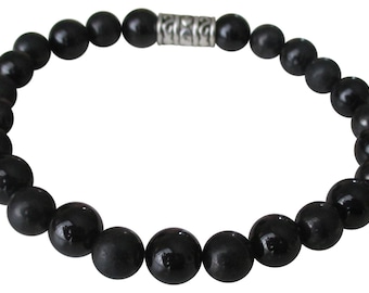 Puede incluir: Un brazalete de cuentas negras con un cierre de metal plateado. Las cuentas son redondas y lisas.