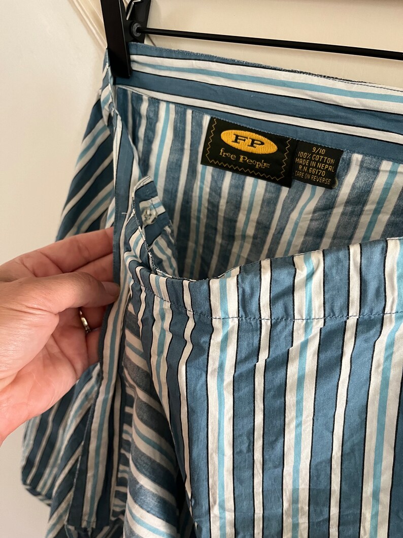 May include: Blue and white striped cotton skirt with a Free People label. The label says "100% cotton made in Nepal RN 66170 care on reverse."