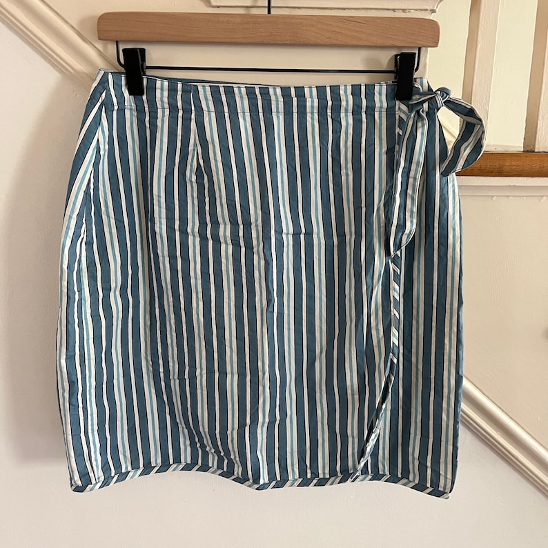 May include: A blue and white striped wrap skirt with a tie at the waist.