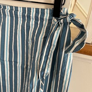 May include: A blue and white striped wrap skirt with a tie at the waist.