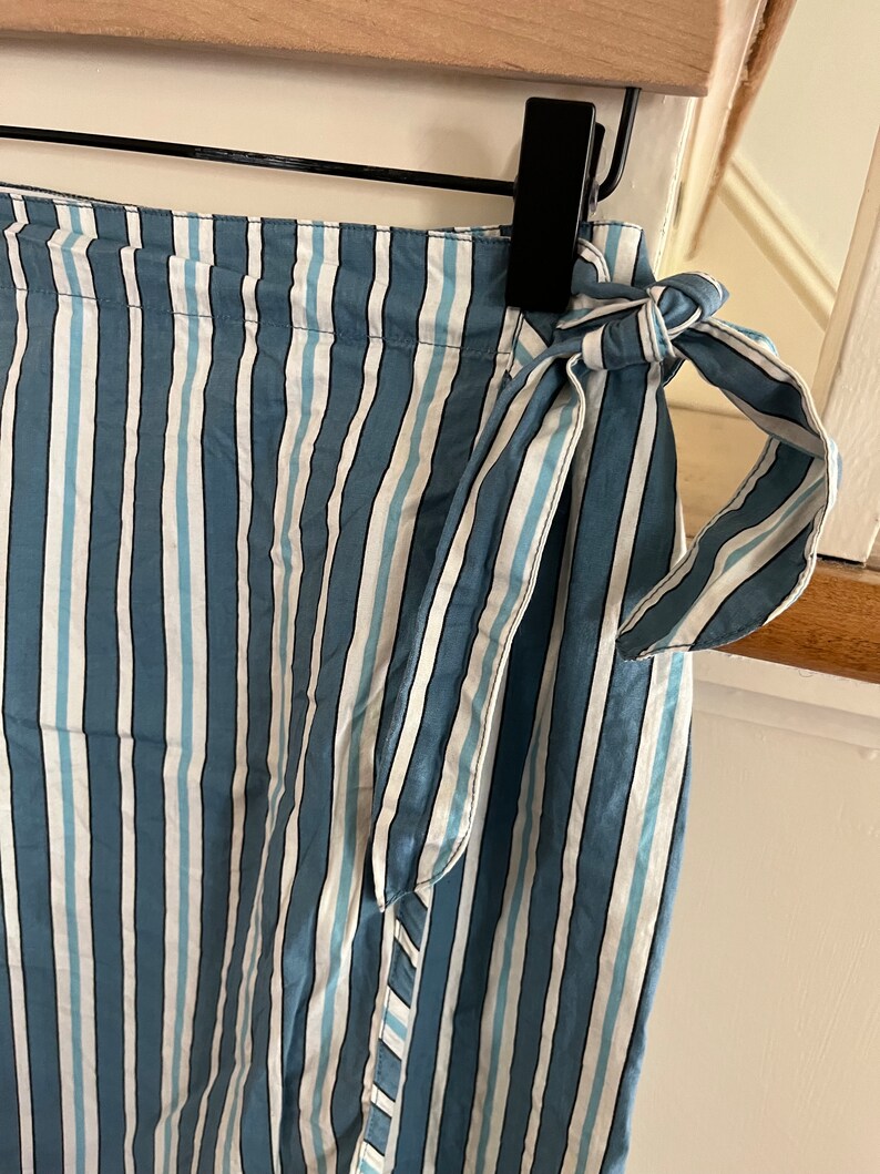 May include: A blue and white striped wrap skirt with a tie at the waist.
