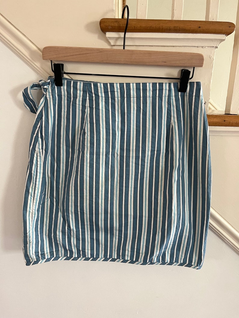 May include: A blue and white striped skirt with a tie at the waist.