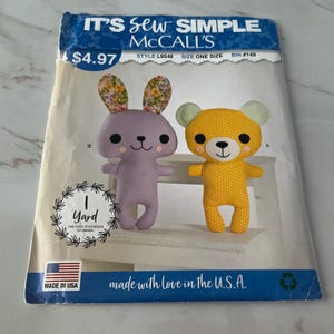 May include: Sewing pattern for two plush toys: a purple bunny with floral ears and a yellow bear with green ears. The pattern is titled "It's Sew Simple McCall's" and costs $4.97. The pattern requires 1 yard of fabric.