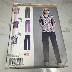 May include: A sewing pattern for scrubs with a floral print top and pants. The pattern includes instructions for making a matching scrub cap. The pattern is designed and printed in the USA. The pattern number is 1020.