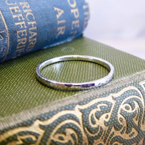 May include: A hammered silver ring on a green book with gold accents.