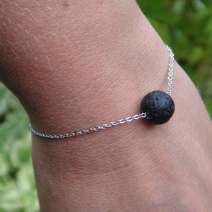 Op de afbeelding: Een zilveren kettingarmband met een enkele zwarte lavastenen kraal.