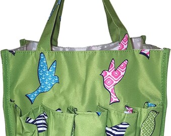 May include: Green tote bag with multiple pockets and a bird print design. The birds are pink, blue, and white with geometric patterns.