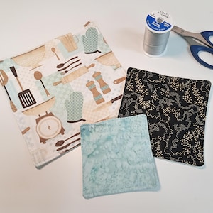 May include: Three fabric squares with different patterns. One square has a white background with a brown and green kitchen theme pattern. Another square has a black background with a gold dot pattern. The third square has a light blue background with a white and blue marbled pattern.