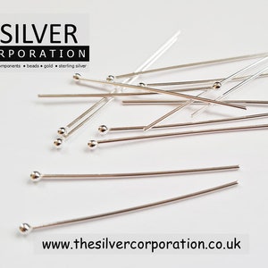 May include: A close-up of a pile of silver head pins. The pins are approximately 2.5 cm long and have a small ball at the end. The pins are used for jewellery making.