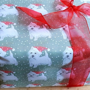 Könnte beinhalten: Eine grüne Geschenkbox mit einem weißen West Highland Terrier Muster. Die Box ist mit einem roten Band gebunden und hat eine festliche Ausstrahlung.