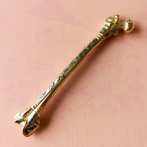FERAL FEMUR - Handpoker, Tätowiernadelhalter aus vergoldetem Messing und kalt emailliert, in Form eines Oberschenkelknochens