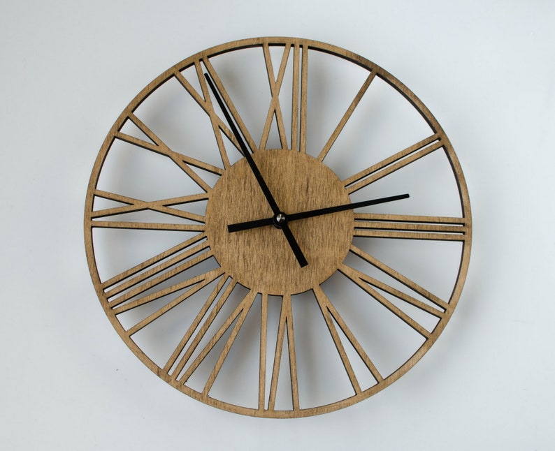A brown wooden clock with black hour and minute hands. The clock face has a circular design with Roman numerals and a wood grain texture. The clock is a decorative wall clock.