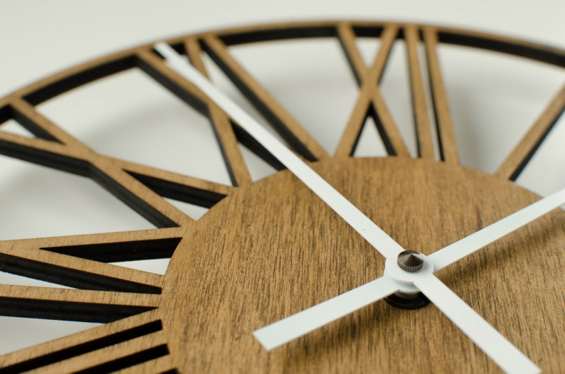 May include: A close-up of a wooden clock face with white hands. The clock face has a unique design with black lines radiating out from the center.