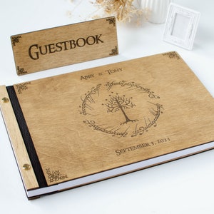 Pu&ograve; includere: Un libro degli ospiti in legno con una rilegatura in pelle nera e un design inciso a laser dell'Albero Bianco di Gondor dal Signore degli Anelli. La copertina include anche i nomi "Abby & Tony" e la data "3 settembre 2023".