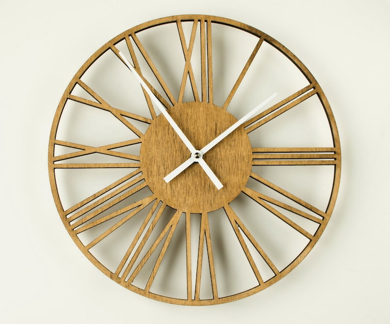 A large, round, wooden clock with white Roman numeral markings and white hour and minute hands. The clock face is a light brown wood with a darker brown wood frame.