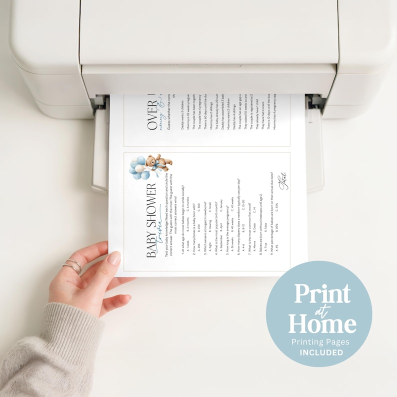 May include: A printer is shown printing baby shower game sheets. The sheets have a blue teddy bear graphic and the words "Baby Shower" and "Over". The bottom right corner of the image has a blue circle with the words "Print at Home" and "Printing Pages Included".