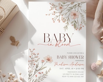 May include: Baby shower invitation with floral illustrations. The invitation features the words "Baby in Bloom" in a stylish font. The invitation includes details such as the date, time, location, and RSVP information.
