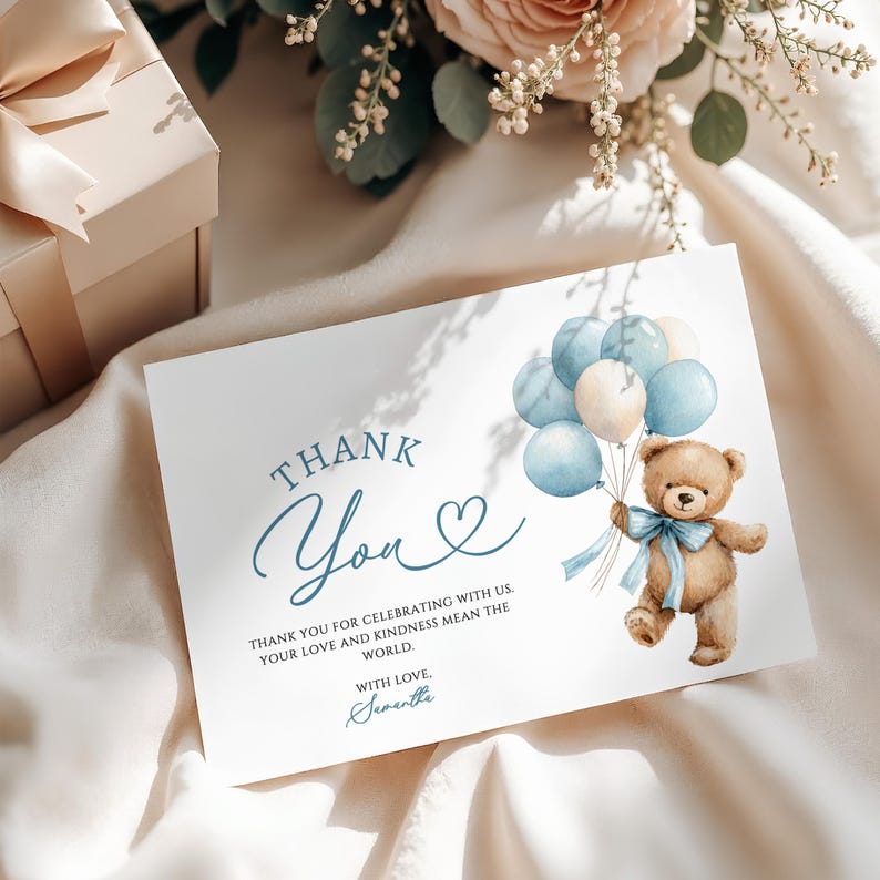 May include: A white card with the words "Thank You" in blue script, a heart symbol, and a watercolor illustration of a teddy bear holding blue and cream balloons. The card also includes the text "Thank you for celebrating with us. Your love and kindness mean the world."