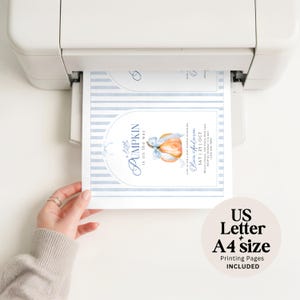 Puede incluir: Una impresora blanca que expulsa una tarjeta de invitaci&oacute;n para baby shower con una calabaza naranja en acuarela, un lazo azul claro, bordes a rayas azules y el texto A little PUMPKIN is on the way para Olivia Anderson.