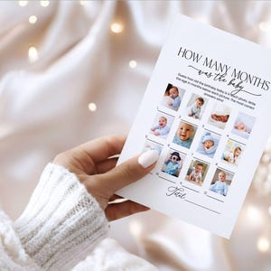 Pode incluir: Um cart&atilde;o branco com o texto "HOW MANY MONTHS was the baby" e uma grade de fotos de beb&ecirc;s. O cart&atilde;o &eacute; segurado por uma pessoa vestindo um su&eacute;ter branco. O cart&atilde;o &eacute; para um jogo de ch&aacute; de beb&ecirc;.