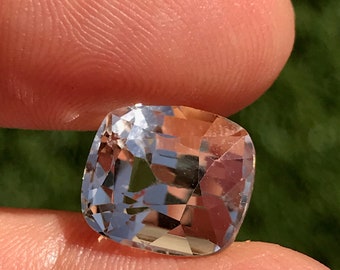 May include: A clear, faceted, cushion-cut gemstone with a light blue hue.