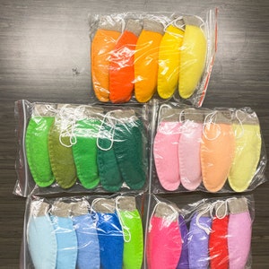 May include: Three bags of felt ornaments in various colors. The first bag contains orange, yellow, and light yellow ornaments. The second bag contains green, dark green, and forest green ornaments. The third bag contains light blue, blue, green, pink, purple, and red ornaments.