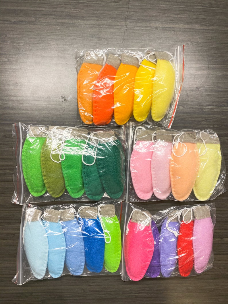 May include: Three bags of felt ornaments in various colors. The first bag contains orange, yellow, and light yellow ornaments. The second bag contains green, dark green, and forest green ornaments. The third bag contains light blue, blue, green, pink, purple, and red ornaments.