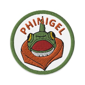May include: Green and orange embroidered patch with the text "PHINIGEL" and a cartoon frog wearing a hat.