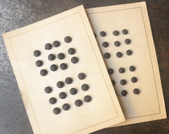 May include: Two cards with black buttons arranged in rows. The buttons are round and have a textured surface.