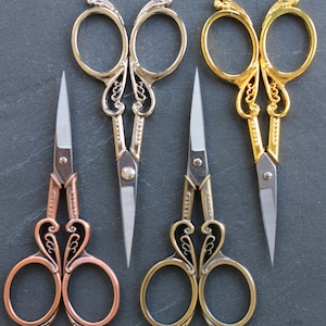 Peut inclure: Trois paires de ciseaux décoratifs avec des poignées ornées. Les ciseaux sont de couleur argent, or et cuivre.