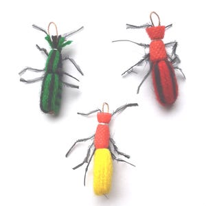 Pode incluir: Três insetos de feltro feitos à mão com antenas de penas pretas. Os insetos são verde e preto, vermelho e preto e vermelho e amarelo.