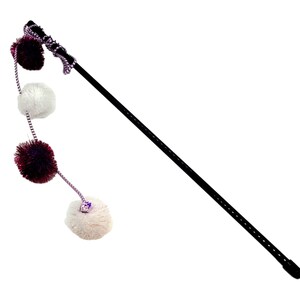 May include: A black wand with a purple and white pom-pom attached to the end. The wand is about 24 inches long and has a black tip. The pom-pom is made of soft, fluffy material.
