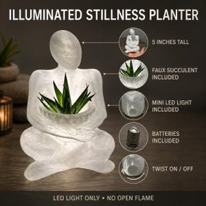 May include: An illuminated stillness planter featuring a translucent white figure in a seated pose holding a green faux succulent. The planter is 5 inches tall, includes a mini LED light with batteries, and features a twist on and off mechanism.