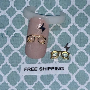 May include: Gold-colored glasses and a lightning bolt nail art design on a light pink nail.  FREE SHIPPING text is visible on a white label.