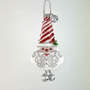May include: A white beaded Christmas ornament shaped like Santa Claus with a red and white candy cane hat and silver bells.