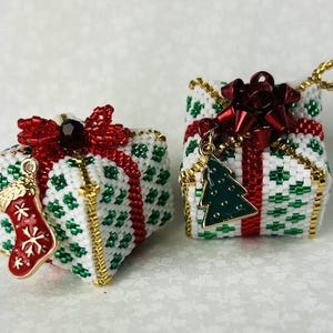 May include: Two small, intricately beaded Christmas ornaments shaped like presents. One is red, white, and green with a gold trim and a small stocking charm. The other is red, white, and green with a gold trim and a small Christmas tree charm.