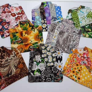 Könnte beinhalten: Eine Sammlung von Stoffkleidersäcken mit verschiedenen floralen und gemusterten Designs. Die Taschen verfügen über eine Aufhängeschlaufe und bestehen aus Patchwork-Stoff. Designs umfassen Sonnenblumen, Gänseblümchen und Paisley-Muster.