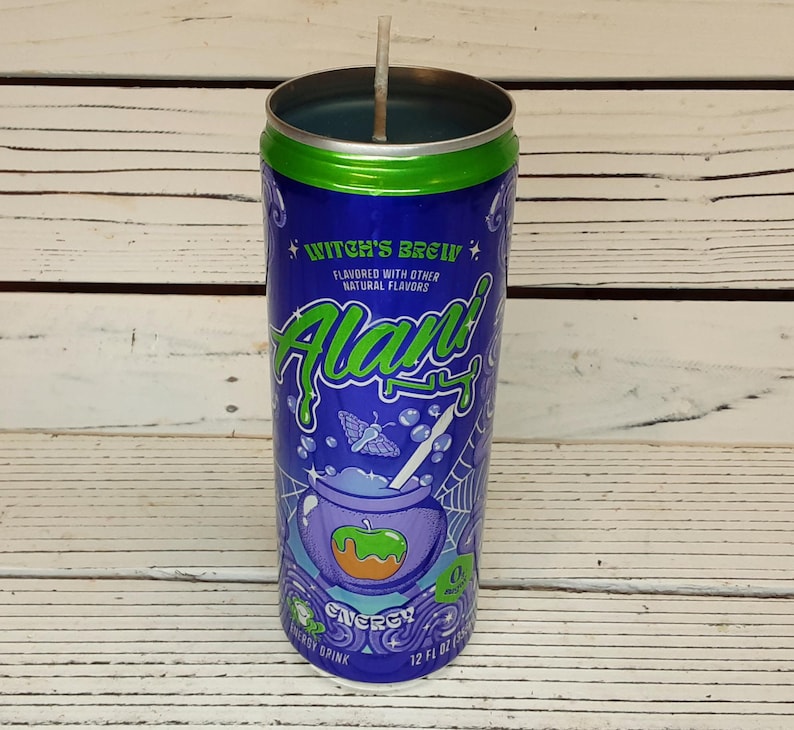May include: A blue and green candle in a can, labeled "Witch's Brew". The can features a cauldron graphic with a green apple and orange accents, along with the text "Alan". The candle is 12 fl oz.
