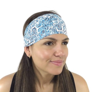 May include: A white headband with a blue paisley pattern. The headband is worn by a person with long brown hair.