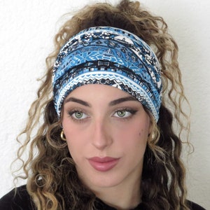 May include: A blue and white patterned headband with a geometric design. The headband is worn by a person with curly hair.