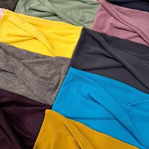 May include: A collection of fabric swatches in various colors and textures, including yellow, blue, green, gray, and purple. The fabrics are arranged in a layered, overlapping pattern, showcasing their different textures and colors.