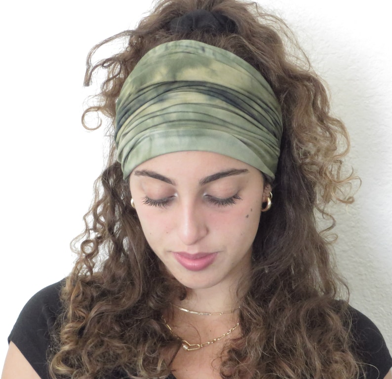 Puede incluir: Una diadema ancha verde oliva con dise&ntilde;o tie-dye. La tela est&aacute; fruncida y envuelta alrededor de la cabeza. La diadema est&aacute; hecha de un material suave y est&aacute; dise&ntilde;ada para mantener el cabello fuera de la cara. El dise&ntilde;o tie-dye presenta tonos verdes y negros.