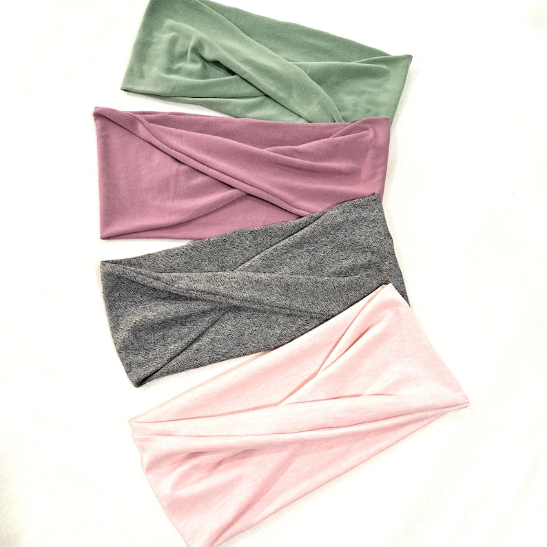 May include: Four twisted headbands in different colors: green, pink, gray, and light pink. The headbands are made of a soft, stretchy fabric.