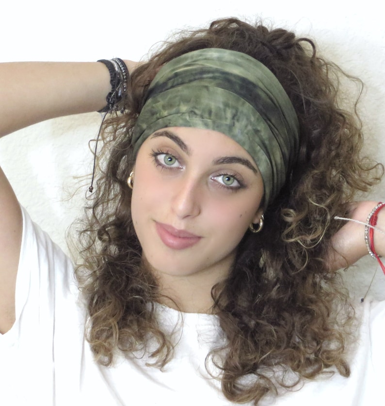 Puede incluir: Una diadema te&ntilde;ida con tinte verde y negro. La diadema est&aacute; envuelta alrededor de la cabeza. La persona de la imagen lleva una camiseta blanca y pendientes de aro dorados. La persona tiene el pelo casta&ntilde;o rizado y ojos verdes.