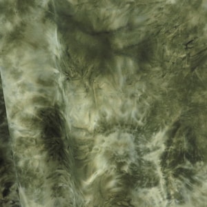 Puede incluir: Primer plano de una tela con un estampado tie-dye en tonos verdes y blancos. La tela tiene un aspecto suave y fluido, con los colores mezcl&aacute;ndose en un dise&ntilde;o arremolinado. La tela se utiliza probablemente para ropa o decoraci&oacute;n del hogar.